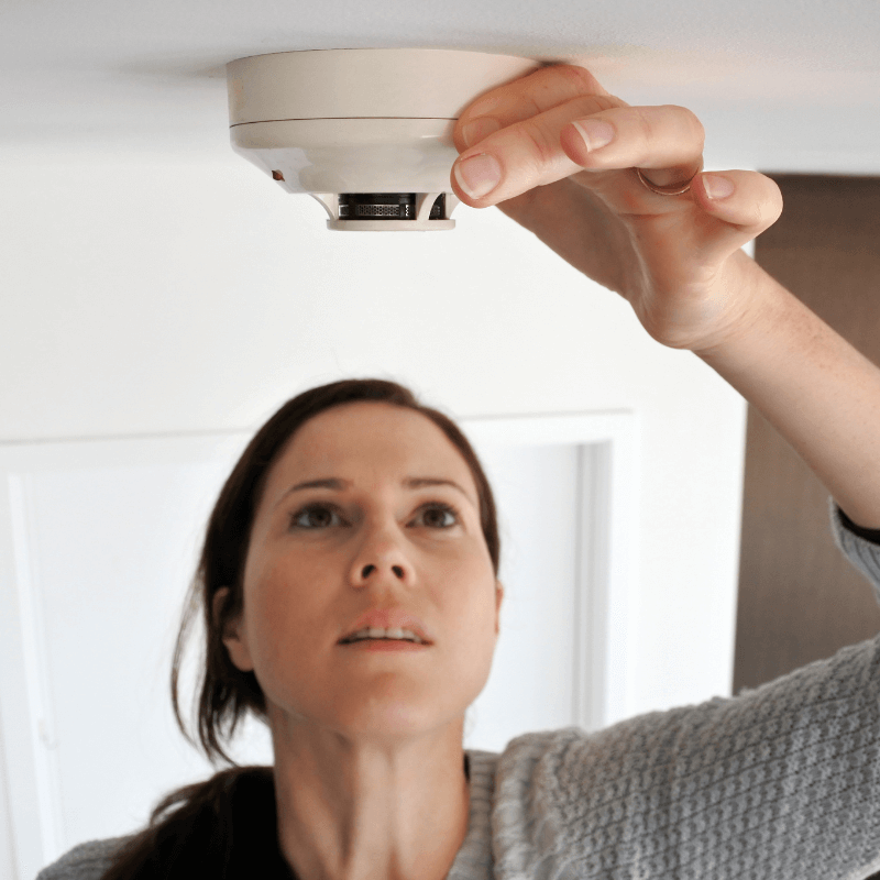 Woman checking her home fire alarm